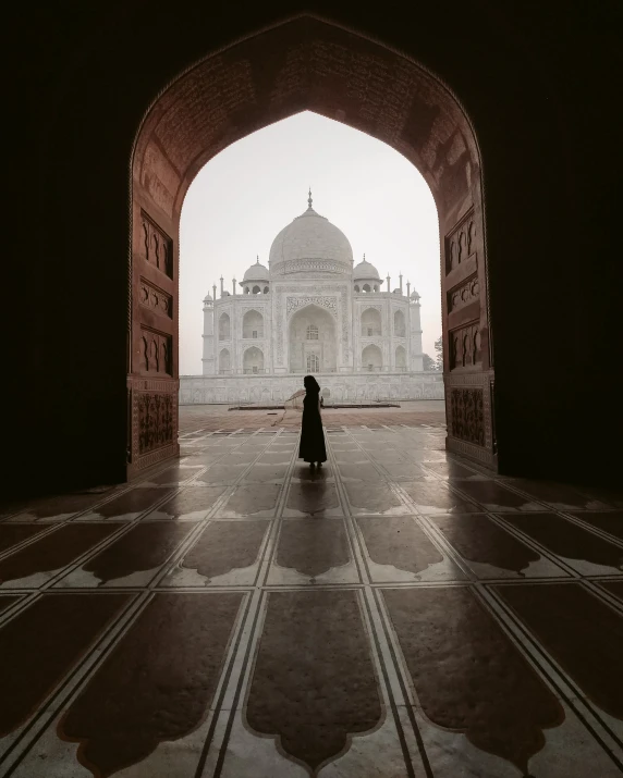 a woman in black standing in front of an archway