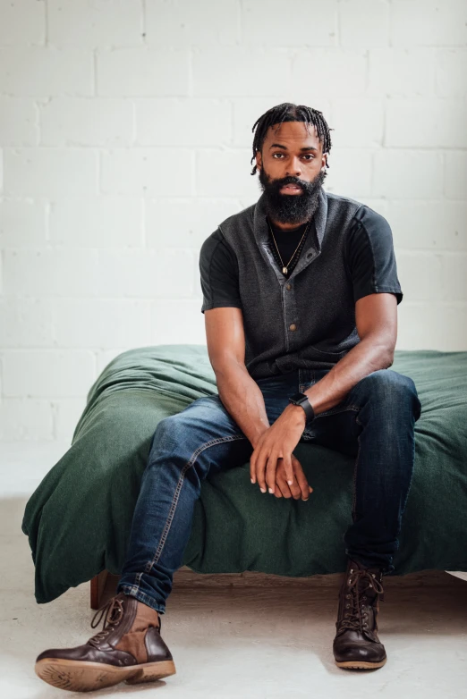 a man sits on an unmade bed in the bedroom