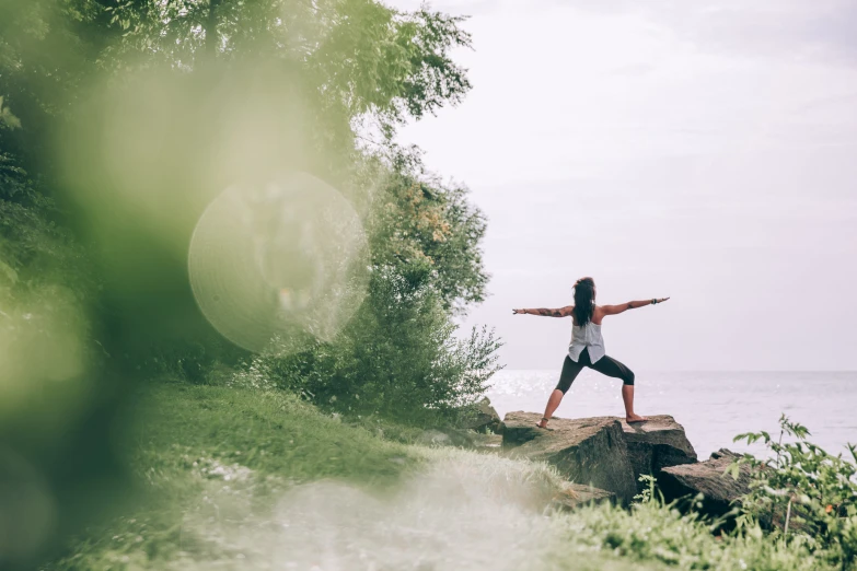 a woman is doing a yoga position on a rock overlooking the water