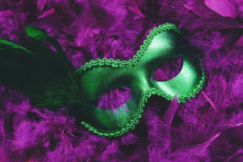 a green mask with feathers is on purple paper