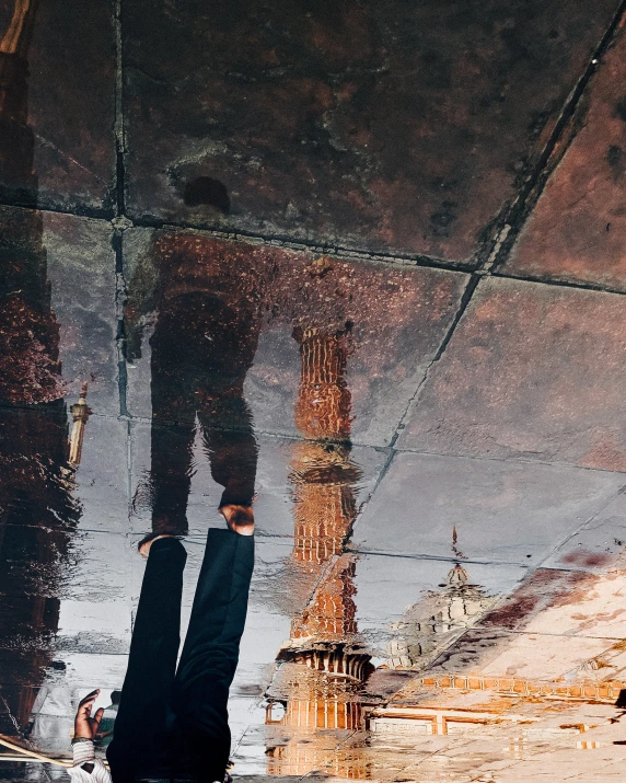 the reflection of a man's legs in a dle on a city street