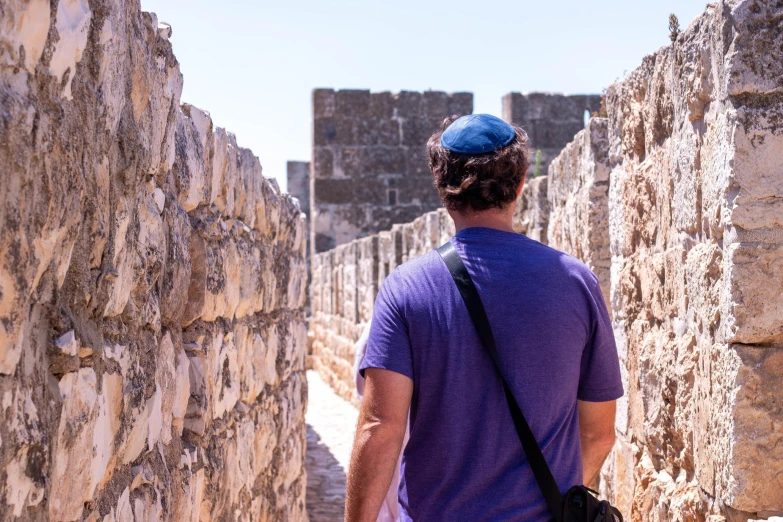 man wearing a blue headband standing between stone buildings