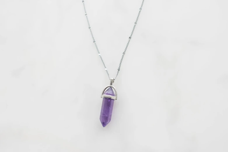 a pendant with a purple gems on a white background