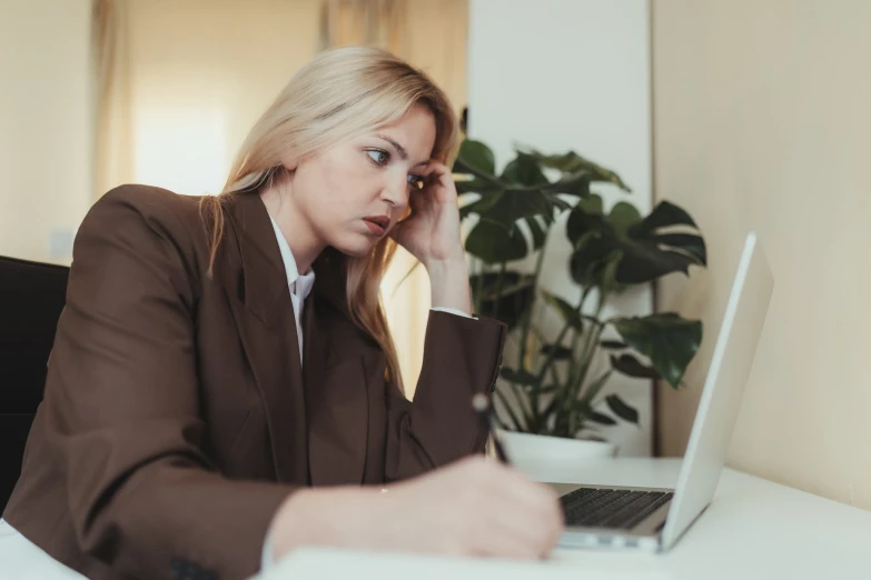 a woman with a brown jacket sitting in front of a laptop computer