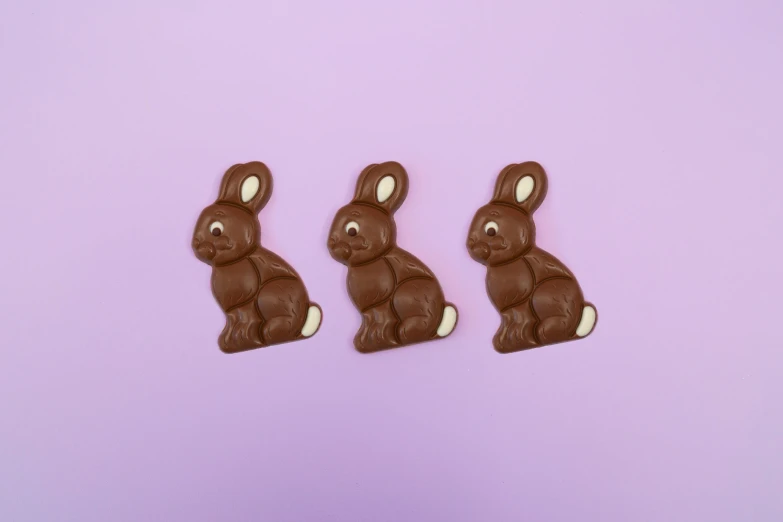 three chocolate shaped bunny rabbits against a pastel background