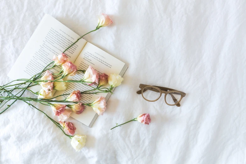 some flowers laying out on a white sheet with glasses