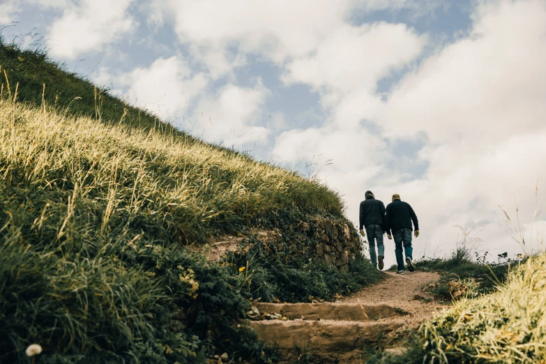 two people are walking up a hill together