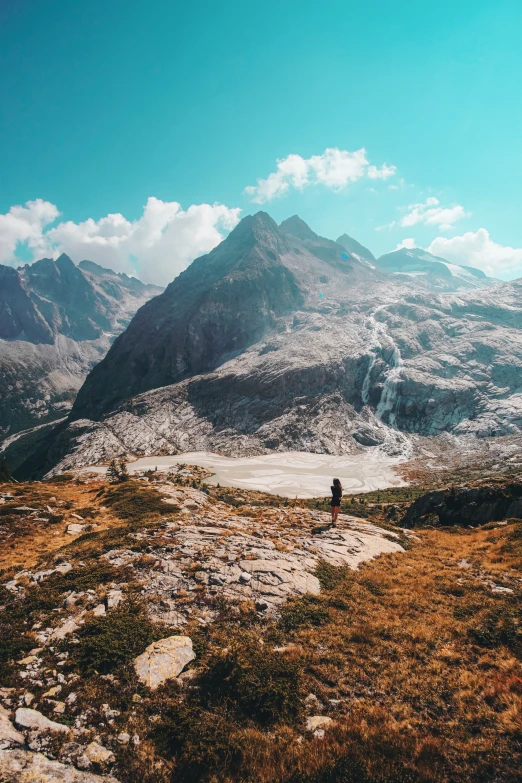 the man stands on the mountain near his hiking gear