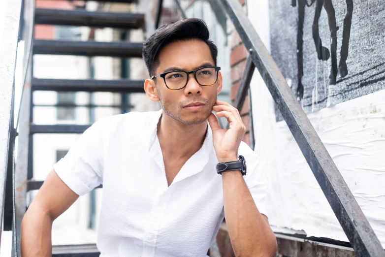 a man in white shirt holding his hand up to his ear