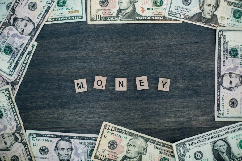 wooden cubes spell out money on a black surface