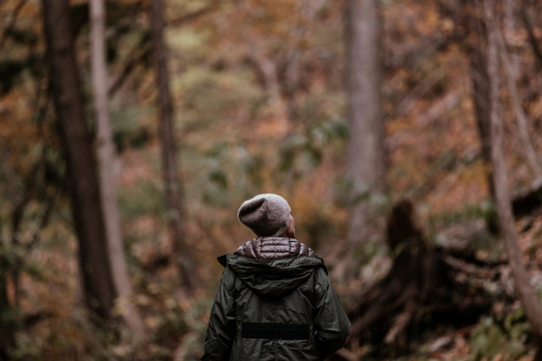 a person wearing a hat walks through a woods in the autumn