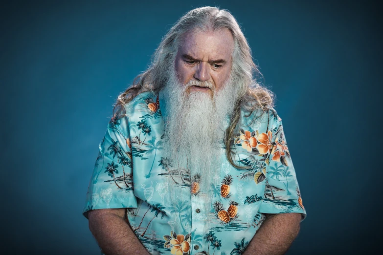 a man in a floral shirt with long white beard looking at his cell phone