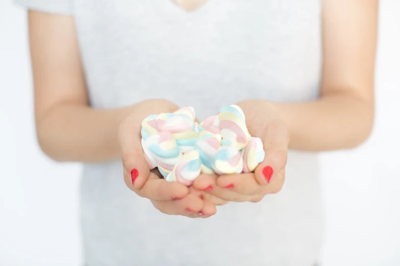 a woman holding out candy that looks like hearts