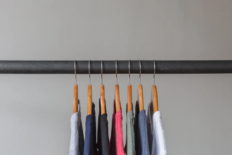 several pairs of multi colored umbrellas hanging from black pipe