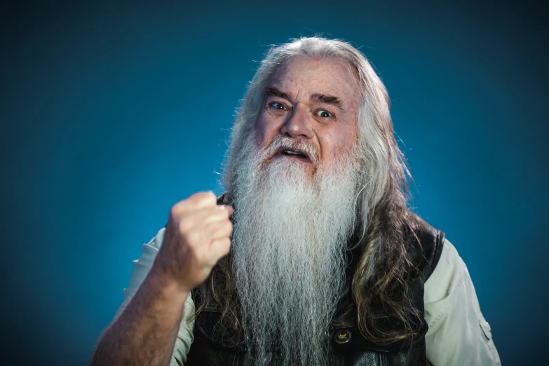 an older man with long white hair wearing a vest