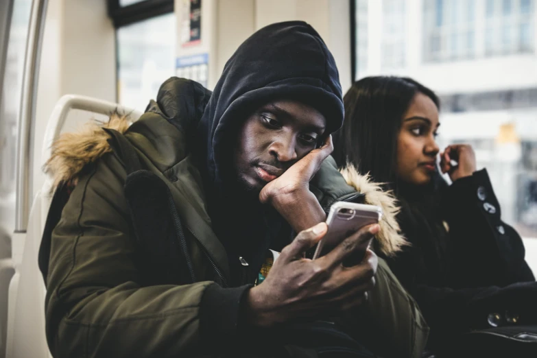 man sitting on a subway looking at his phone