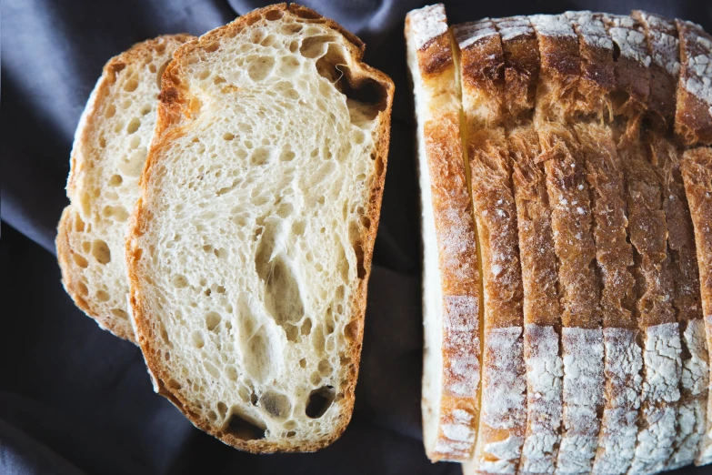 two pieces of bread on the table and one slice being sliced