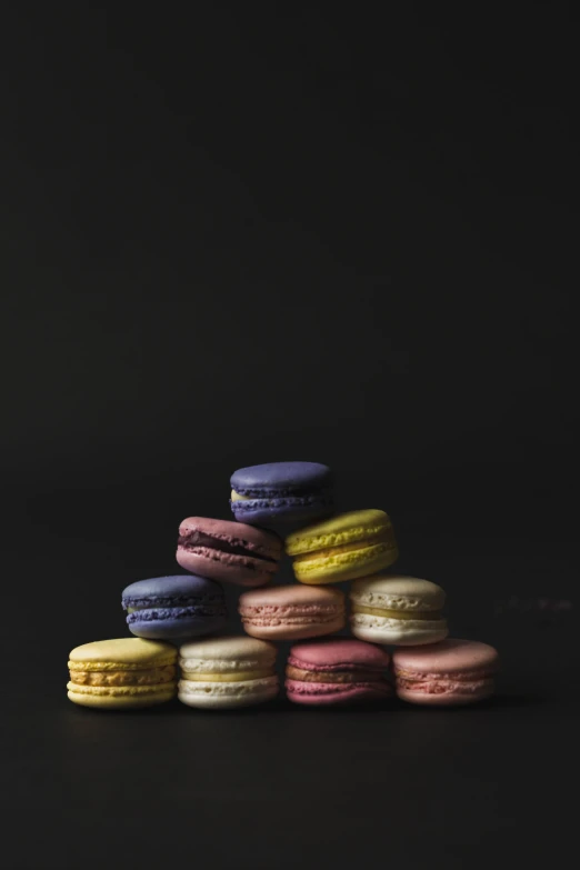 macaroons stacked in different colors on a dark surface