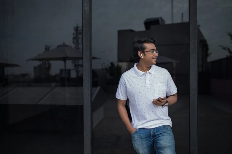 a man standing in front of a window wearing a white polo shirt