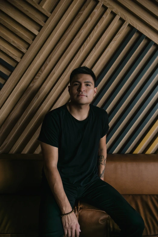 a young man sitting on top of a brown leather couch