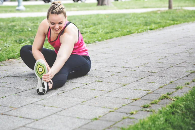 a woman tying up her sneakers on the ground