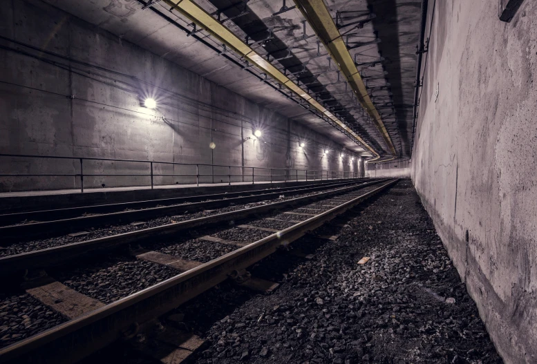 a dimly lit subway station with two sets of railroad tracks