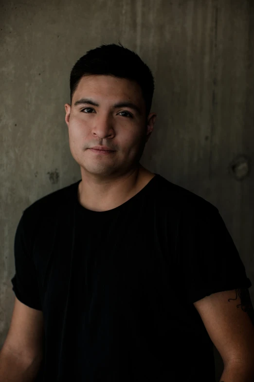 a young man poses in front of a wall