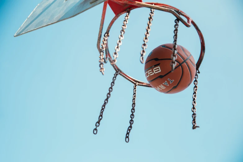 a basketball and a piece of metal hanging off the rim of a basketball hoop