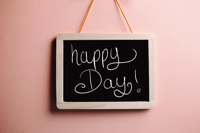 the blackboard hanging on the wall says happy day