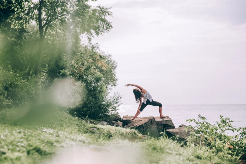 a woman standing on top of a rock next to the ocean