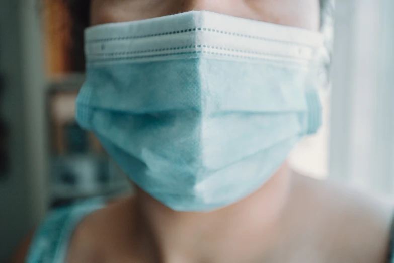 a woman wearing a mask and looking out the window