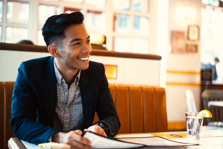 a man smiling sitting at a table and holding papers