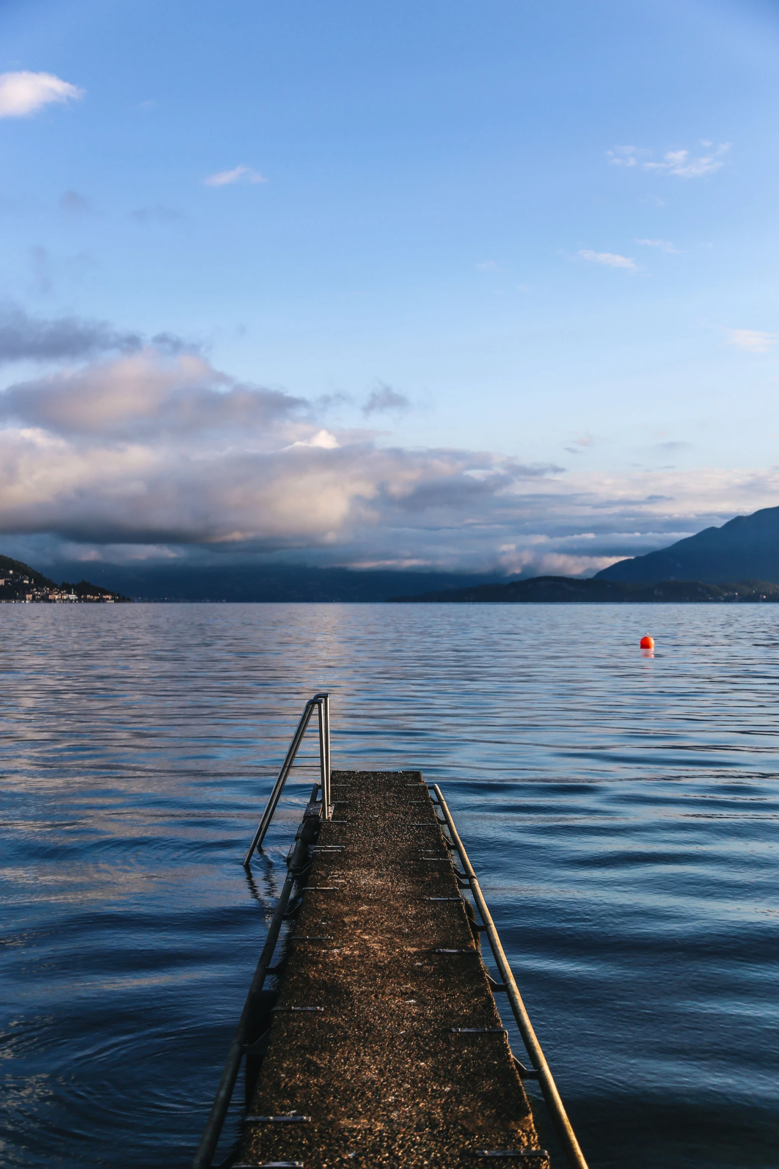 a pier next to the water with mountains in the background