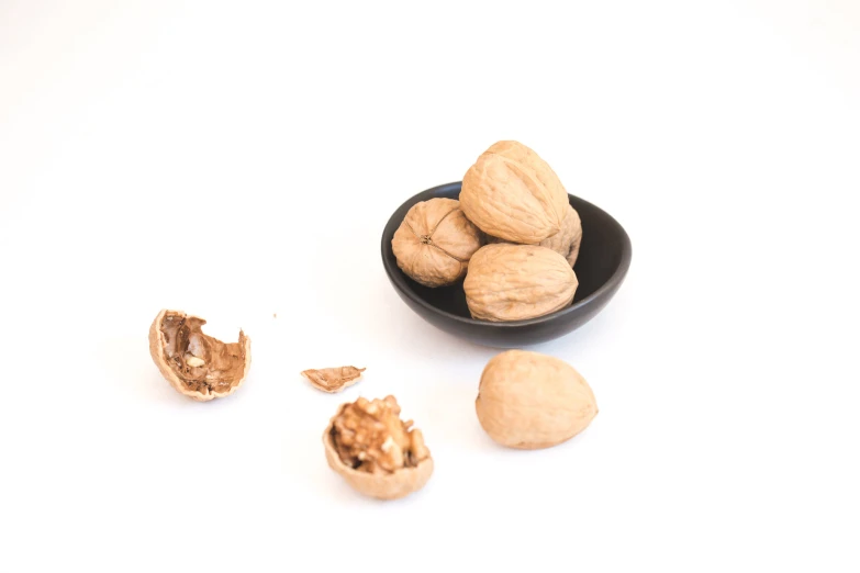 some nuts are in a bowl and next to it is a broken one