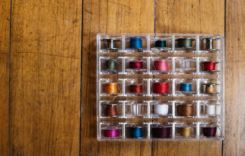 an open box on top of a wooden floor filled with lots of spools