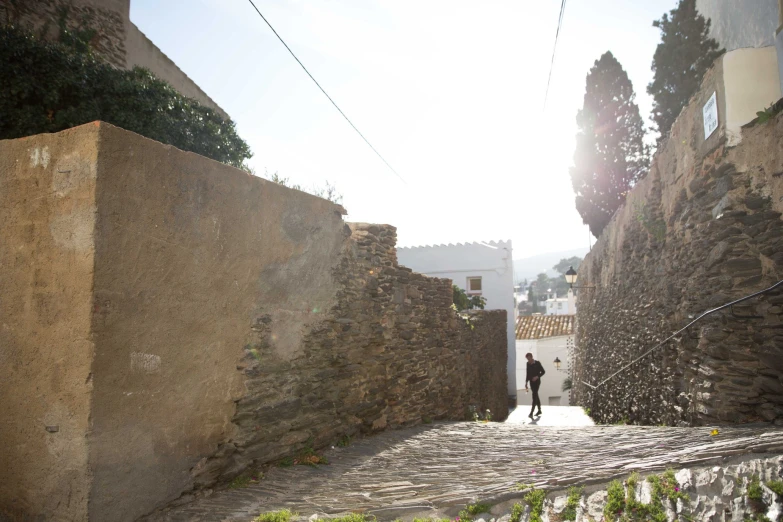 a person walking down a cobblestone street in an alley