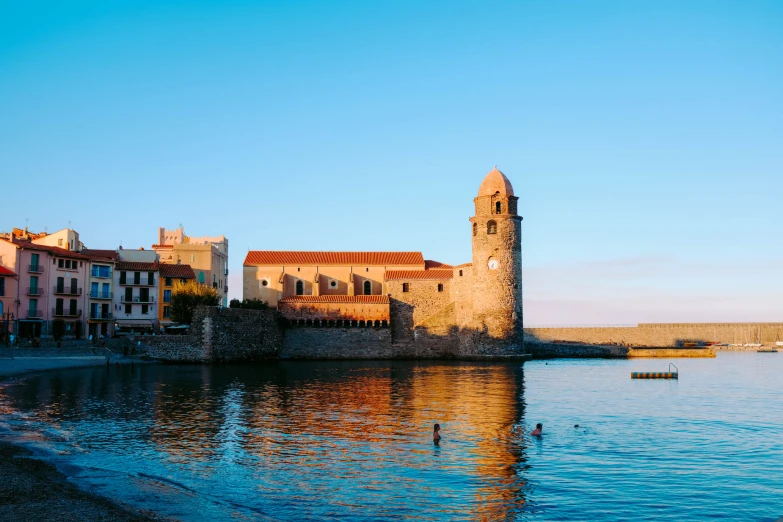 a city near the water with a tall tower and buildings