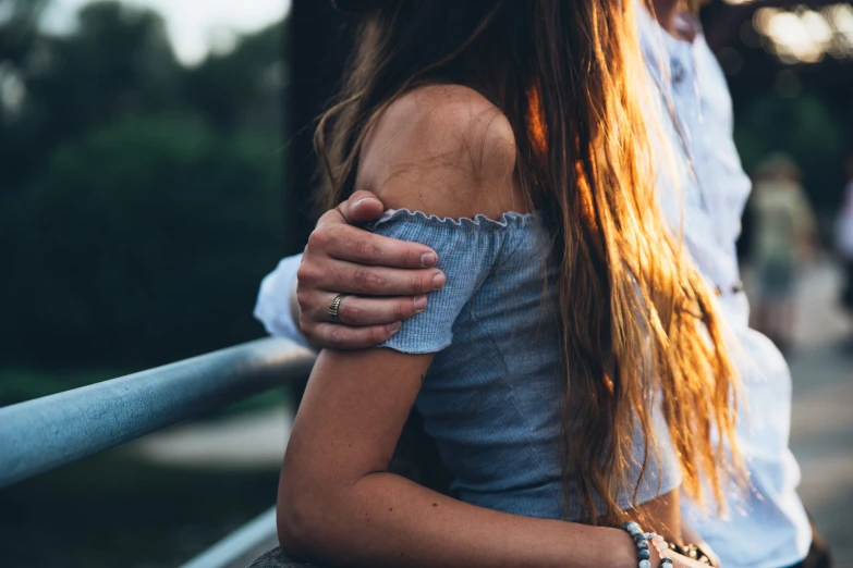 an affectionate couple emcing each other near a fence