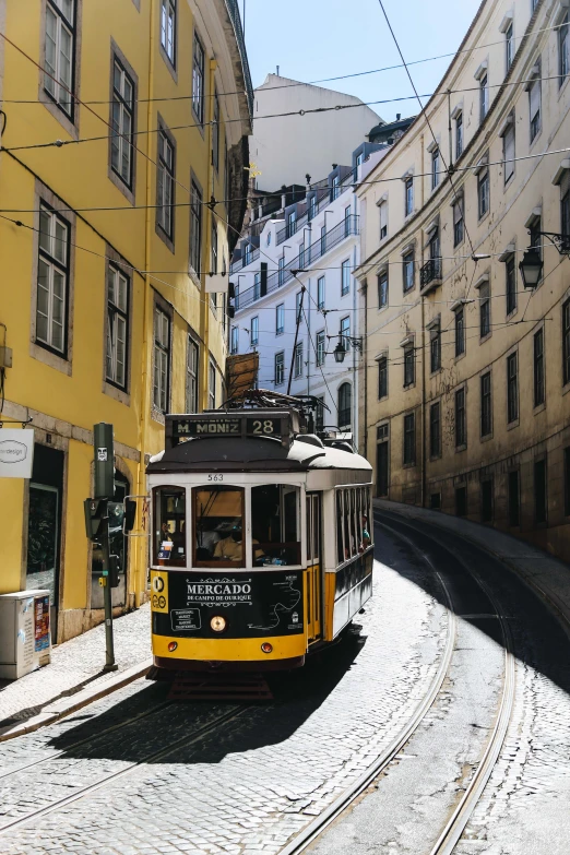 the trolley is traveling down the cobblestone road