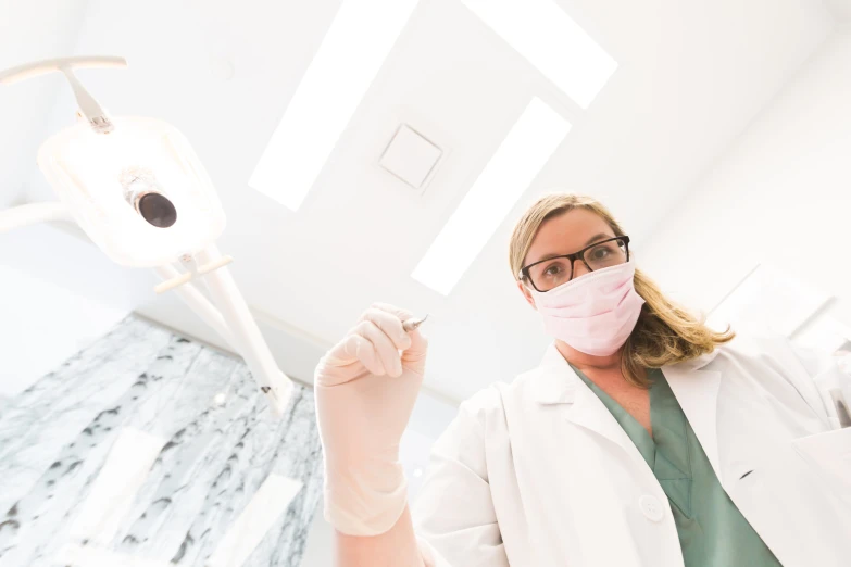 the dentist wears a pink face mask and is holding a toothbrush