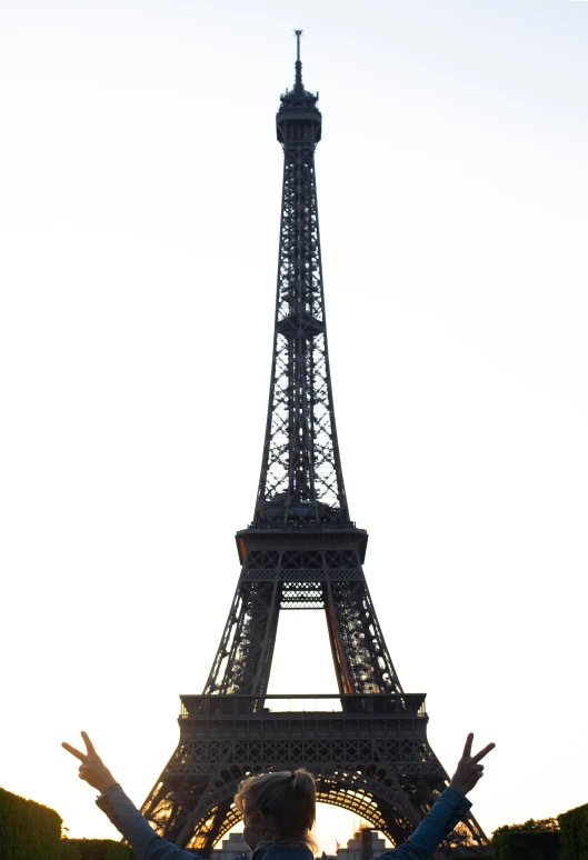 two people standing on grass near a tall eiffel tower