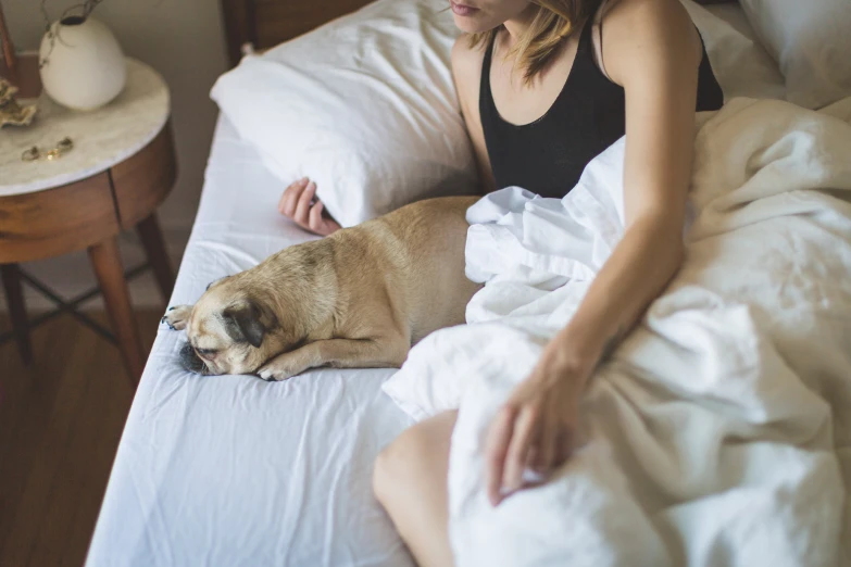 a woman is sleeping in bed with her dog