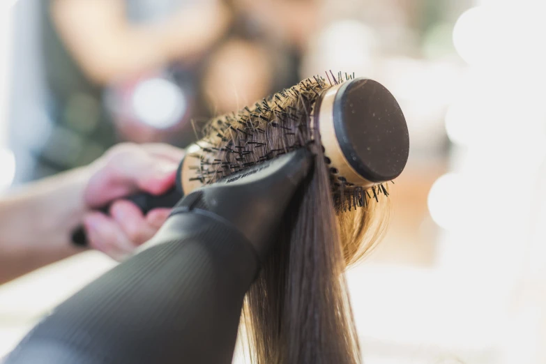 a person holding a hairdryer and brush with its right hand