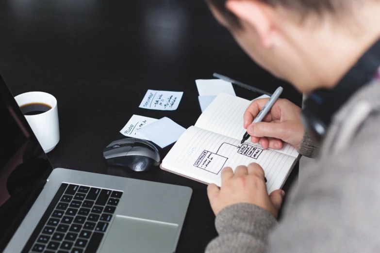 a person sitting at a table writing with a note book