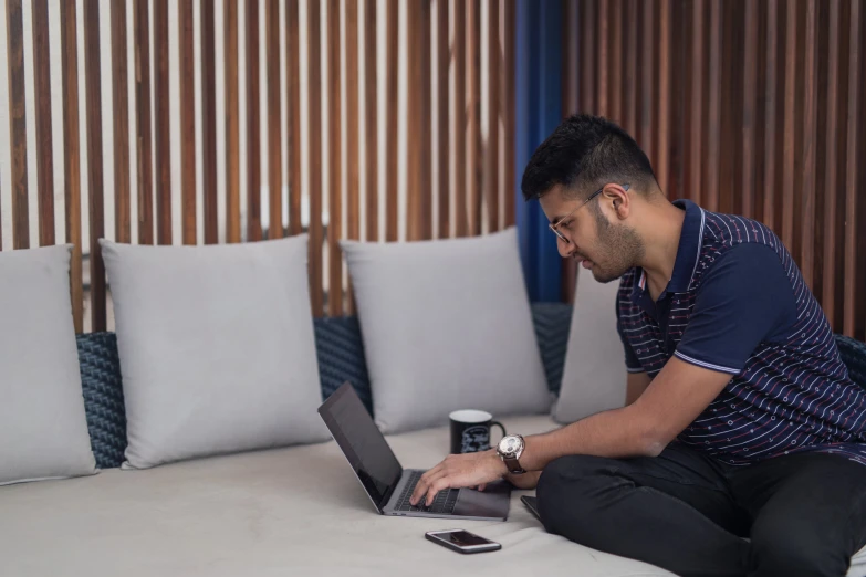 the man is using his laptop on the bed