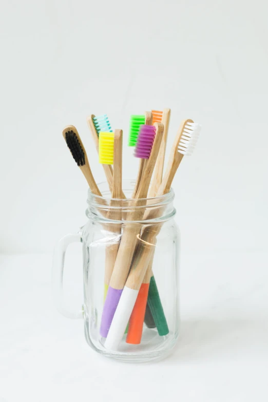 a jar holding lots of toothbrushes that have been dipped in color