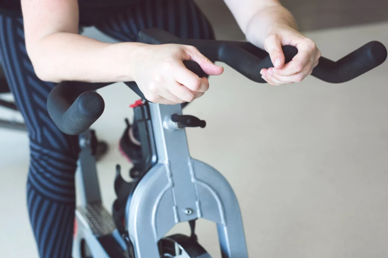 a woman with her hand on the handle bars of an exercise bike