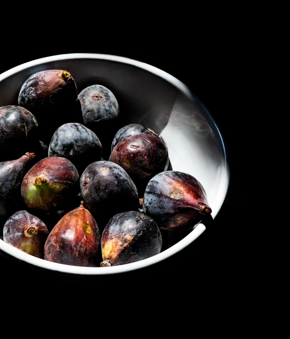 some figs are sitting in a silver bowl