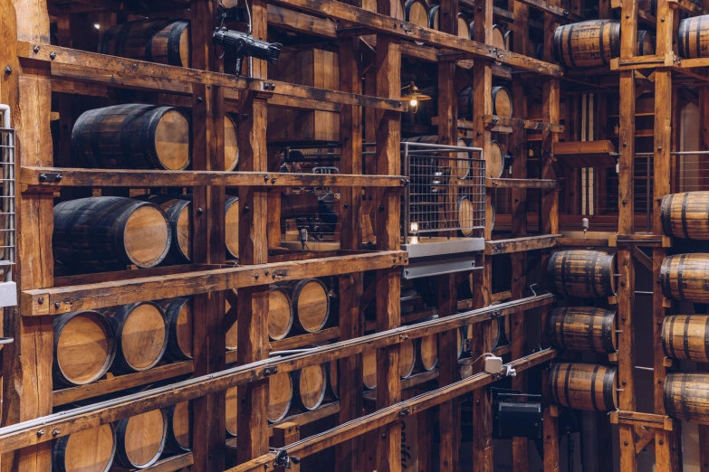 wooden barrels of wine sit in rows in a room