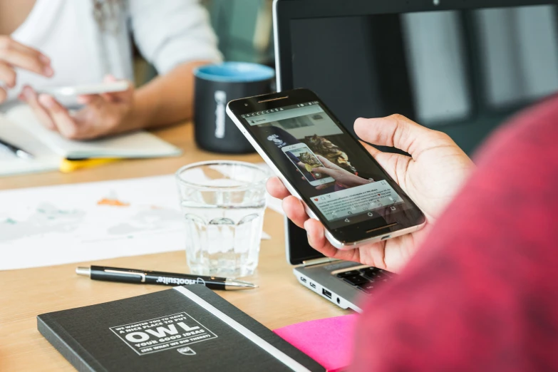 two people sitting at a table looking at their phones